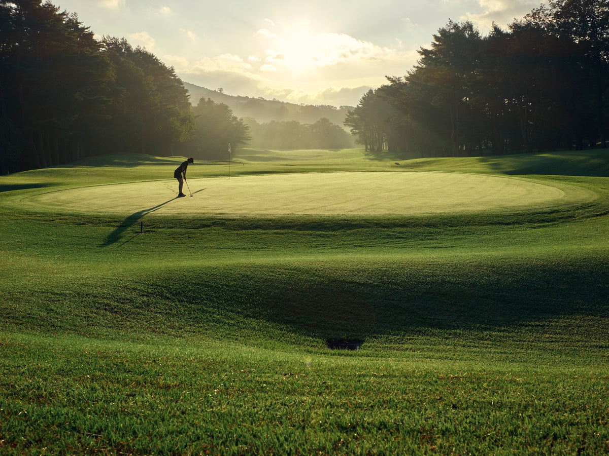 Golfer putting on a Kagosaka Course green at golden hour